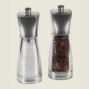 The Cole & Mason UK Rye Salt & Pepper Mill Set 160mm includes clear and stainless steel mills with ceramic mechanisms, pre-filled with coarse salt and whole black peppercorns.