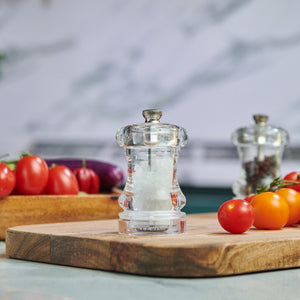 #85mm#salt
The Cole & Mason Acrylic Capstan Salt & Pepper Mills sit on a wooden cutting board with fresh vegetables, bringing style and elegance to kitchen dining settings with their clear design against a marble backsplash.