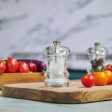 #85mm#salt
The Cole & Mason Acrylic Capstan Salt & Pepper Mills sit on a wooden cutting board with fresh vegetables, bringing style and elegance to kitchen dining settings with their clear design against a marble backsplash.