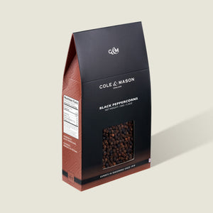The Cole & Mason Black Peppercorns Box features a rectangular black and brown design with a clear window to view the peppercorns. Ideal for pepper mills, it ensures fresh seasoning. The front displays the brand and product name.