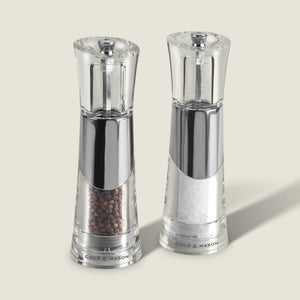 The Cole & Mason Bobbi Salt & Pepper Mill Set features two clear, modern mills with silver accents, adjustable grinders, and durable mechanisms. Each is prefilled with black peppercorns or coarse sea salt and labeled Cole & Mason at the base.