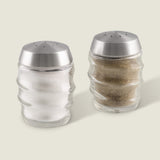 The Cole & Mason Bray Glass Shakers Set features two clear glass shakers with stainless steel tops and a wavy design—one for salt, one for pepper—placed side by side, ideal for any kitchen décor.
