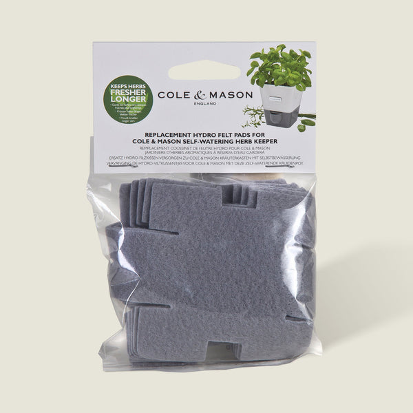 A set of gray, cross-shaped absorbent pads from Cole & Mason UK for the Burwell Self Watering Potted Herb Keeper Small and Tealby Herb Keeper, visible in clear packaging with branded labels and herb illustrations.
