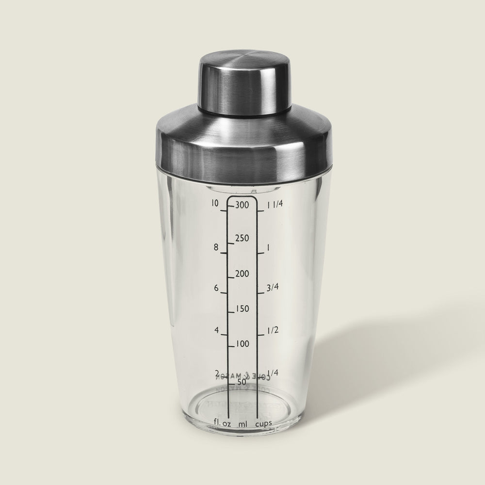 The Cole & Mason Cambourne Salad Dressing Shaker features clear glass with a stainless steel lid and measurement lines in ounces, milliliters, and cups—ideal for mixing cocktails, vinaigrettes, or dressings on any surface.