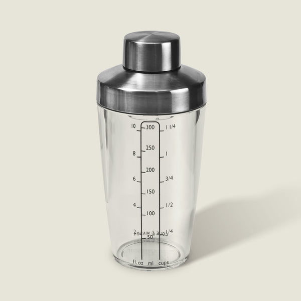 The Cole & Mason Cambourne Salad Dressing Shaker features clear glass with a stainless steel lid and measurement lines in ounces, milliliters, and cups—ideal for mixing cocktails, vinaigrettes, or dressings on any surface.