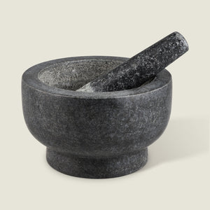 The Cole & Mason Clavering Pestle & Mortar is a dark gray granite set with the pestle inside the bowl—an essential, traditional kitchen tool ideal for home chefs.