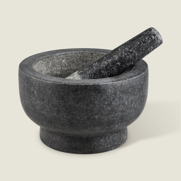 The Cole & Mason Clavering Pestle & Mortar is a dark gray granite set with the pestle inside the bowl—an essential, traditional kitchen tool ideal for home chefs.