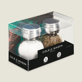 The Cole & Mason Darlington Shakers Set features a stylish glass and stainless steel design, attractively packaged in a clear box with bold branding and a colorful leaf pattern background for extra flair.