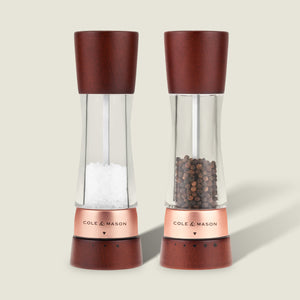 #salt&pepperset
The Cole & Mason Derwent Chestnut Rose Gold Salt & Pepper Mills—featuring clear acrylic bodies, rose gold accents, and chestnut wood tops and bases—stand upright on a light background with salt in one and peppercorns in the other.
