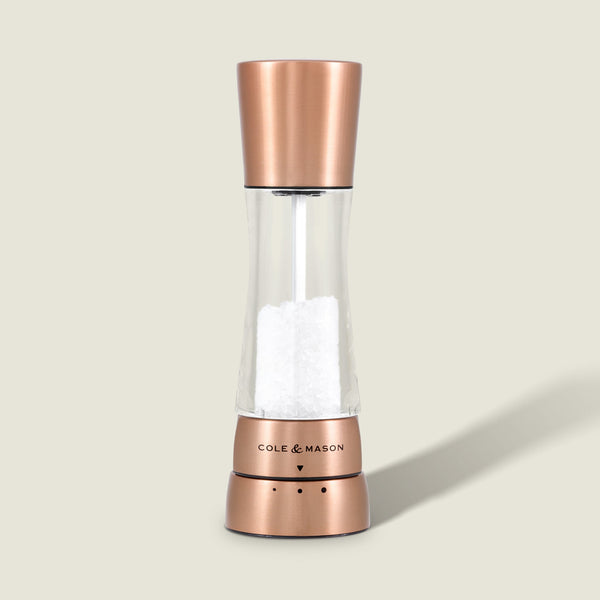 The Cole & Mason Derwent Copper Salt & Pepper Mills feature a sleek, modern design with a transparent body to display white salt crystals and stylish copper accents, blending contemporary aesthetics with precise grinding technology.
