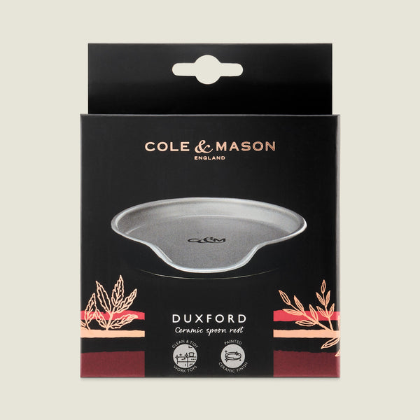 The Cole & Mason Duxford Ceramic Spoon Rest comes in a sleek black box, featuring a grey rest with gold and pink accents—an elegant touch for your kitchen.
