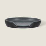 The Cole & Mason Duxford Ceramic Spoon Rest is a black, round ceramic piece with a raised edge and front cutout—perfect for kitchen decor and shown against a light cream background.