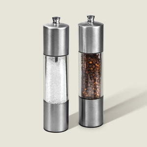 The Cole & Mason Everyday Stainless Steel Salt & Pepper Mill Set features an ergonomic design and adjustable coarseness; both mills stand upright on a light background, one containing coarse salt, the other whole black peppercorns.
