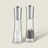 The Cole & Mason Everyday Style Salt & Pepper Mill Set includes two clear glass grinders with stainless steel tops and adjustable settings—ideal for any kitchen. One holds salt, the other peppercorns, displayed side by side on a light background.