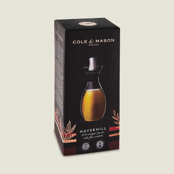 A black box displays the Cole & Mason Haverhill Oil & Vinegar Pourer, highlighting its precision spout and featuring an image of the glass pourer filled with golden liquid on the front.