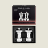The Hoxton Silver Plated Salt & Pepper Mill Set by Cole & Mason features two elegant mills in a sleek black box with brand and product details—ideal for stylish dining.