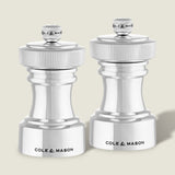 The Cole & Mason Hoxton Silver Plated Salt & Pepper Mill Set stands side by side on a light background, showcasing a sleek, modern design with ribbed tops and compact bases—ideal for elegant dining.