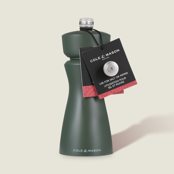 A dark green Cole & Mason Kenton Salt & Pepper Mill in Rosemary with a ceramic mechanism and silver top, plus a black tag for salt or pepper, is shown on a light background.