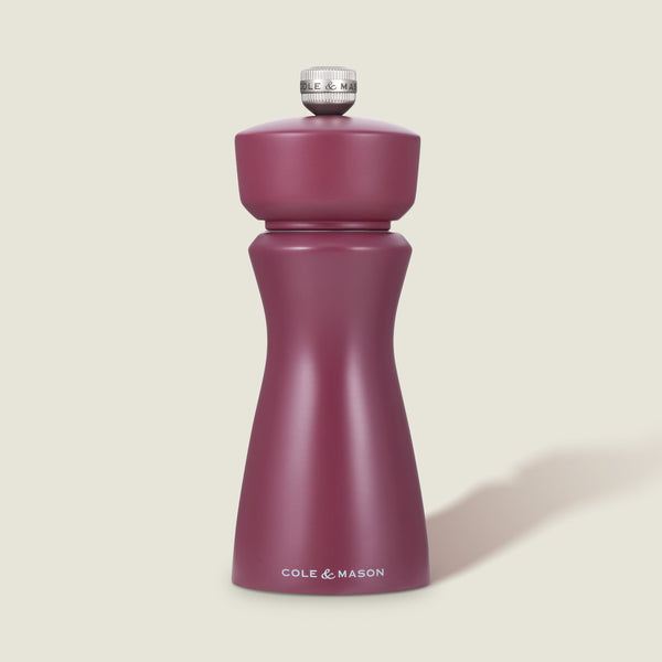 The Cole & Mason Kenton Sichuan Pepper Red Salt & Pepper Mill, with a matte burgundy finish, ceramic mechanism, and silver top knob, stands upright on a plain light background with the brand logo in white near its base.