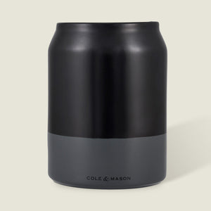 The Cole & Mason Linton Ceramic Utensil Pot, a matte black and gray soda can-shaped container with branding near the base, is ideal for storing cooking utensils and shown against a light beige background.