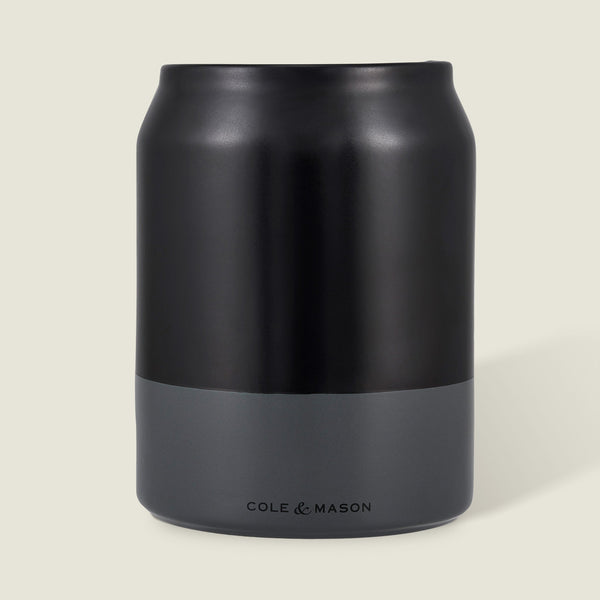 The Cole & Mason Linton Ceramic Utensil Pot, a matte black and gray soda can-shaped container with branding near the base, is ideal for storing cooking utensils and shown against a light beige background.