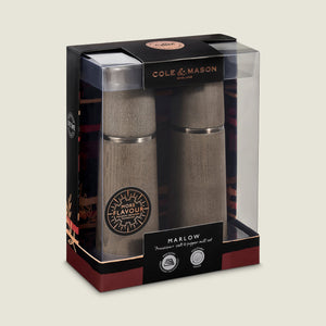 The Cole & Mason UK Marlow Grey Beech Salt & Pepper Mills set features stylish mills with adjustable grinding, packaged in a branded clear display case showing product details.