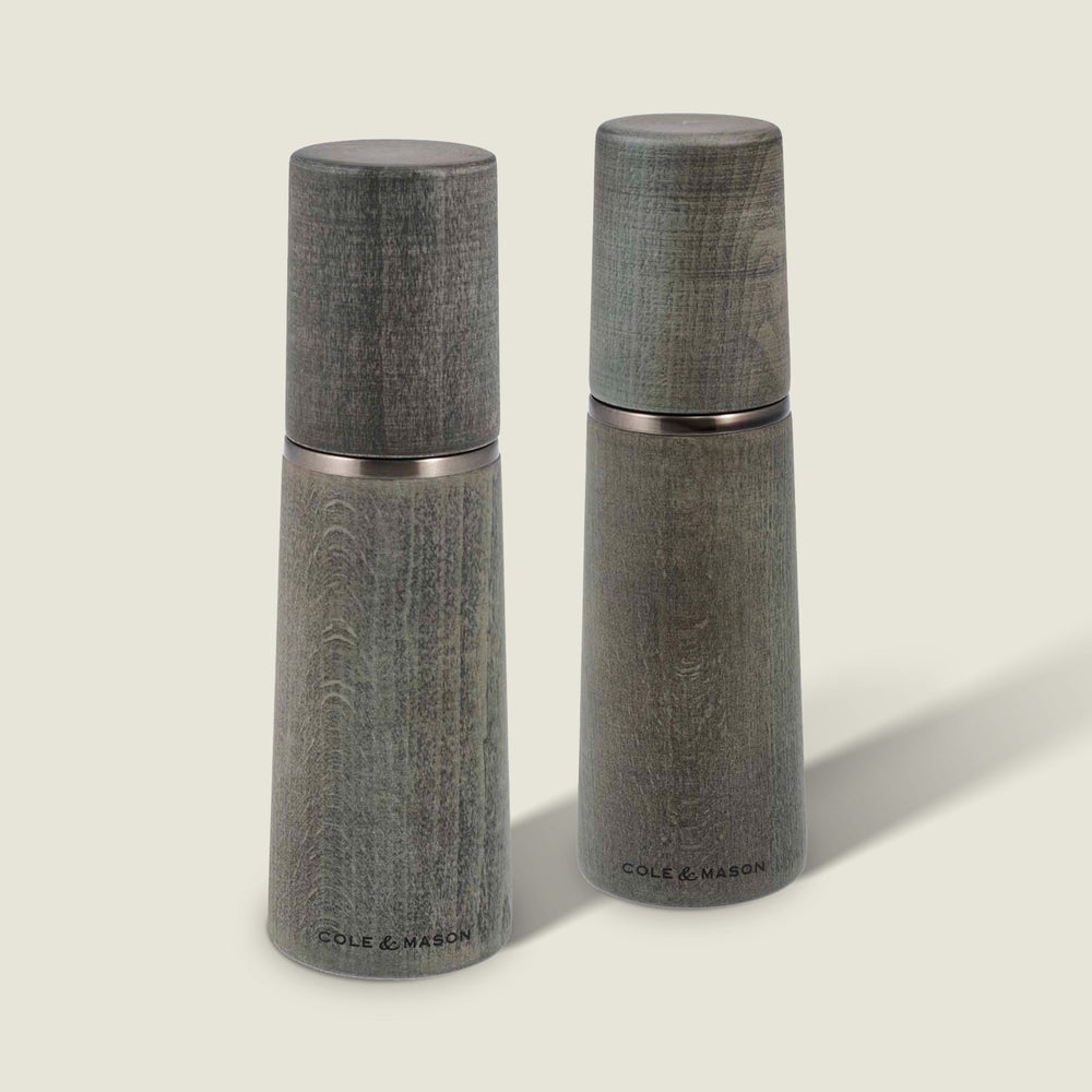 Two Marlow Grey Beech Salt & Pepper Mills by Cole & Mason UK, featuring a smooth tapered shape and wood grain, stand upright on a light background with an adjustable grinding mechanism for custom seasoning.